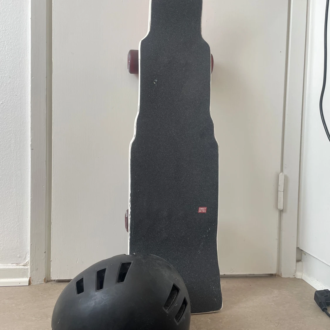 Svart skateboardhjälm med ventiler samt en skateboard