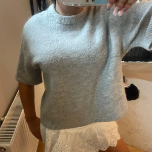 Kortärmad stickad tröja  - Super fin ljusgrå, kortärmad stickad tröja från Gina Tricot. Tröjan har används fåtal gånger, vilket gör den i väldigt fin skick. Storlek M men passar S. Skriv för funderingar💖