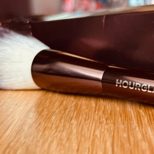 Veil Powder brush från Hourglass! - Veil Powder brush från Hourglass är en dubbelsidig makeupborste som fångar upp rätt mängd puder. Den smala, vinklade sidan är perfekt för området kring ögonen och den stora, runda borsten är designad att användas för hela ansiktet. Penseln är tillverkad av ultra-mjukt, högkvalitativt taklonfiber. Oanvänd med kartong. 