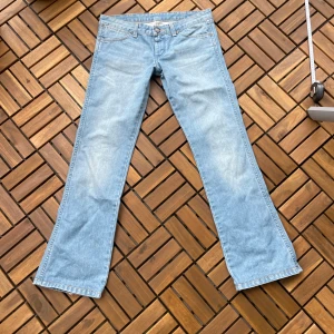 Ljusblå bootcut jeans från Wrangler - Säljer ett par ljusblå bootcut jeans från Wrangler med klassisk femficksdesign och snygga kontrastsömmar. Jeansen har låg midja. Mått: midjemått tvärsöver 39cm (ingen stretch), Innerbenslängden 75cm. Köptes för ganska dyrt därav priset, men de gör att diskutera💗Kolla gärna in allt annat jag säljer!🥰
