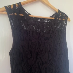 Svart spetsklänning från Stockh LM - Supersnygg svart klänning i spets från Stockh LM. Ärmlös modell med rund halsringning och figurnära passform upptill, lätt utställd kjol. Dragkedja bak och helfodrad under spetsen. Perfekt för dig som gillar klassisk men trendig stil.
