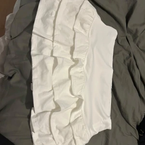 Vit volangkjol  - Supersöt vit kortkjol med flera volanger och hög midja. Kjolen är i mjuk och skön och väldigt fin. Den är aldrig använd 