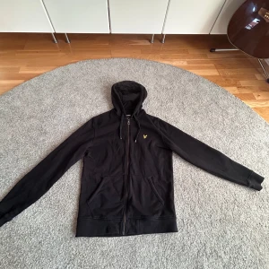Svart hoodie från Lyle & Scott - Svart hoodie från Lyle & Scott med dragkedja. Väldigt skön och snygg men jag har inte använt den så mycket. Nypris ca 900 kr. Bra skick, inga fläckar eller hål. 