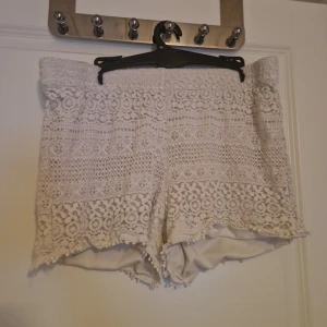 Vita spetsiga shorts - Superfina vita shorts med spets och volangkant. De har ett romantiskt mönster i spets över hela plagget. Perfekta för sommarens varma dagar och ger en riktigt söt och bohemisk vibe. Lite slitna nere vid låren men inget som syns.