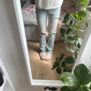 Ljusblå lågmidjade bootcut jeans med hål - Svin snygga low waist utsvängda jeans med egen klippta hål. Jag är 169!