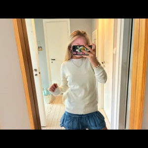 Vit stickad tröja  - Säljer en klassisk vit stickad tröja med rund halsringning och ribbade muddar vid ärmslut och nederkant. Tröjan har en enkel och stilren design som passar perfekt till jeans eller kjol. 