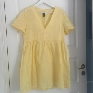 Gul kortklänning med v-ringning H&M - Söt gul kortklänning från H&M med v-ringad hals och korta ärmar. Klänningen har en luftig passform och är gjord i bomull, perfekt för varma dagar. Enkel och stilren design som känns fräsch och somrig.
