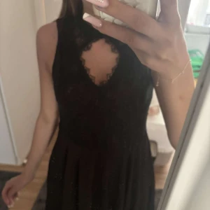 Svart spetsklänning från NLY Trend - Världens finaste klänning/se sista bilden, saknas en liten sån man sätter ihop knappen med en sådan metallbit, ena sidan hel på ryggen saknas den lilla delen som är som err litet knäppe.därav priset inköp 1499, går med synål och tråd eller med vanlig säkerhetsnål.  svart kortklänning från NLY Trend med spets upptill och ärmlös design. Klänningen har hög hals med liten öppning fram och lätt utställd kjol. Perfekt för dig som vill ha en elegant och stilren look med extra detalj i spetsen.