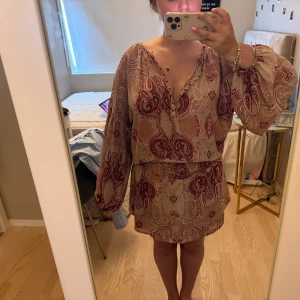 Paisleymönstrad klänning  - Assss snygg unik paisleymönstrad miniklänning med smock i midjan så man kan justera längd och passform själv. Perfekt rosa/beige sommar och festivalklänning. Boho chic vibes🥰🥰Står ingen storlek men passar S-M då man kan justera passformen lite själv.