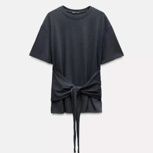 Svart t-shirt med knyt från Zara - Intressekonflikt Svart t-shirt från Zara med cool knyt-detalj i midjan som ger en snygg siluett. T-shirten har rund halsringning och korta ärmar. Perfekt för dig som vill ha en basic men ändå unik look. Endast använd 2 gånger 