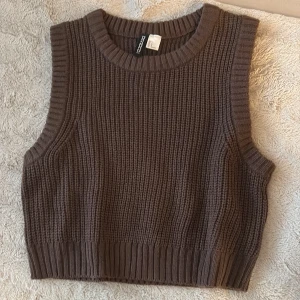 Brun stickad väst  - Säljer en brun stickad väst från divided HM. Västen har grov ribbstickning, rund halsringning och breda muddar vid ärm och nederkant. Perfekt att slänga över en skjorta eller t-shirt för en chill och trendig look.