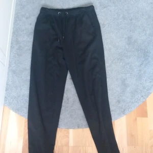 Svarta mjukisbyxor från 157, storlek M - Svarta mjukisbyxor från 157 med elastisk midja och snörning. Byxorna har raka ben och är tillverkade i mjukt bomullsmaterial. Perfekta för chill dagar eller när du vill ha det extra bekvämt. Klassisk look med fickor både fram och bak.