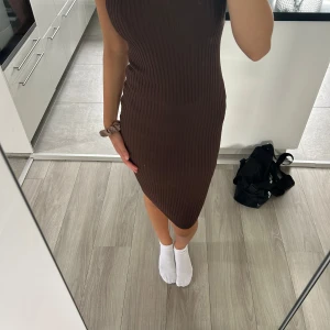 Brun ribbad tight klänning - Säljer en brun, ribbad och tight klänning med ärmlös design. Klänningen är knälång och har en kroppsnära passform som framhäver figuren. Perfekt för dig som gillar en enkel men snygg stil. EU 36😊