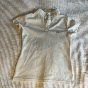 En fin vit beige rid tröja  - En bra fin rid tröja som är vit och är från active riding wear som har andvänds fåtalgånger.Tröjan är en luftig skön tröja a t-shirt  som funkar bra till sommarn men också vid tävlingar 