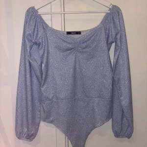 Ljusblå body med småprickigt mönster - Supersöt ljusblå body från Bik Bok med små vita prickar, långärmad och med lätt rynk vid bysten. 