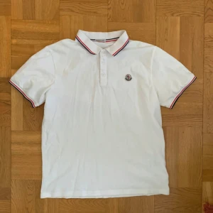 Vit Moncler piké  - Vit pikétröja från Moncler med klassisk krage och knäppning framtill. Var skick. Stl L men passar M