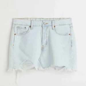 Ljusblå jeanskjol från A Denim - Ljusblå kort jeanskjol med slitna detaljer och fransig nederkant. Klassisk femficksmodell med dragkedja och knapp framtill. Säljer då den aldrig har kommit till användning, skriv kring frågor💞