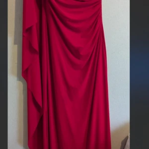 Röd långklänning från Ralph Lauren - Säljer en elegant röd långklänning från Ralph Lauren. Klänningen har draperad design med snygga veck och är tillverkad i ett mjukt, följsamt material. Perfekt för dig som vill sticka ut med en klassisk och tidlös look.