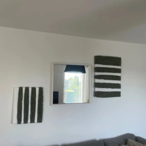 2 Handgjorda Tavlor i garn, 70x50 & 50x40 - Bilderna visar två textila konstverk med gröna och vita ränder, upphängda på en vägg. Det finns ingen bok synlig på bilderna.