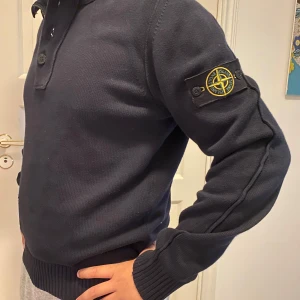 Mörkblå stickad tröja Stone Island - Säljer en mörkblå stickad tröja från Stone Island med klassisk patch på ärmen. Tröjan har ribbade muddar, hög krage med både dragkedja och knappar. Perfekt för dig som gillar streetwear och vill ha något stilrent men ändå med edge vid snabb affär kan även priset diskuteras.