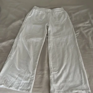 Vita wide mjukisbyxor från Kappahl - Vita mjukisbyxor från Kappahl i storlek 146. Byxorna har elastisk midja, raka och vida ben samt mjukt material som känns skönt mot huden. Perfekta för en chill och avslappnad stil.