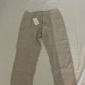 Beige linnebyxor från ZARA - Snygga beige linnebyxor i rak passform med klassiska fickor fram och bak. Oanvända. Storlek 46. Köpta för 500kr.