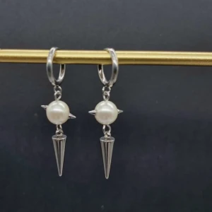 Silvriga örhängen med pärlor och spikes - Coola örhängen i silverfärg med rund vit pärla och spetsig spike-detalj. Hängande modell som ger edgy vibe med mix av klassisk pärla och metalliska detaljer. Perfekt för dig som vill sticka ut med din stil.