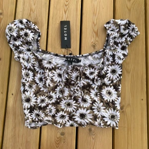 Söt sommartop - Crop top med daisy print från motel rocks. Helt oanvänd med taggen fortfarande fast. Den har en och en annan lösa trådar men det är från produktionen, inte pågrund av användning.                                                       Tags: cottagecore dark academia vintage coquette vintage love vintagelove sommarkläder sommar summer top shirt t-shirt puffed arms blommig flowers pretty cute