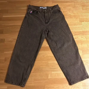 Bruna loose fit jeans - Säljer ett par bruna jeans med loose fit och raka ben. Byxorna har klassisk femficksdesign och en liten broderad detalj på ena fickan. Perfekta för en avslappnad och trendig stil.