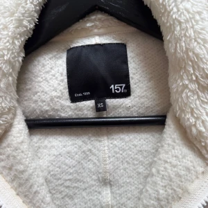 Vit teddyjacka från 157, XS - Mysig vit teddyjacka från 157 i storlek XS. Jackan har hel dragkedja framtill, två stora fickor och hög krage. Säljer pågrund av att den inte kommer till användning längre😊