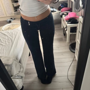 Svarta mjukisbyxor med snörning XS - Svarta mjukisbyxor i mjukt bomullsmaterial med dragsko i midjan. Byxorna har låg midja och raka ben med en relaxed fit. Perfekta för chill dagar eller när du vill vara bekväm men ändå se snygg ut.