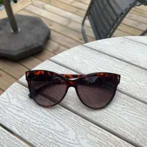 Bruna cat eye-solglasögon i leopardmönster - Snygga solglasögon i cat eye-modell med leopardmönstrad båge i bruna och svarta toner. Glasen är mörka och ger en cool vibe till din look. Perfekta accessoaren för soliga dagar och festivaler.