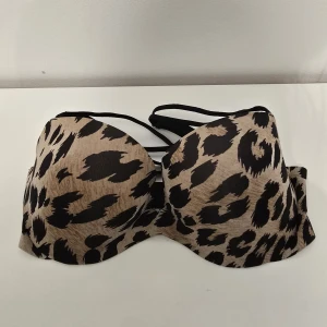 Leopardmönstrad bh från Victoria's secret - Snygg bh från Victoria's secret med leopardmönster i beige och svart. Toppen har vadderade kupor och tunna svarta band som ger en cool detalj. Perfekt för dig som vill sticka ut med ett djurmönstrat plagg.stl 34 D