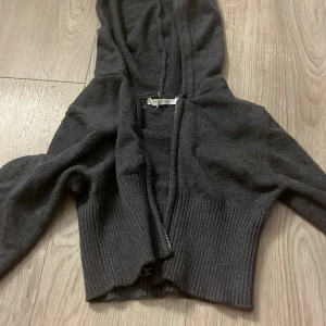 Mörkgrå hoodie från Gina Tricot - Mysig mörkgrå hoodie från Gina Tricot med dragkedja framtill och ribbad mudd nedtill. Tröjan har huva och är långärmad, perfekt för kyliga dagar. Materialet känns stickat och ger en avslappnad känsla. Knappt använd, endast hemma fåtal gånger, minns inte nypris💗