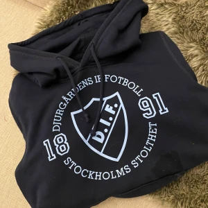 Djurgårdens IF marinblå hoodie - Marinblå hoodie från Djurgårdens IF med stort tryck framtill i ljusblått. Möts ofta upp för lämning i Sthlm men kan skicka 