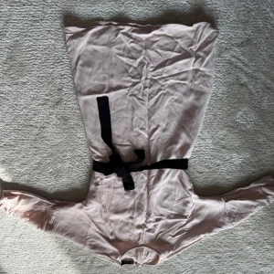 Ljusrosa långärmad klänning STOCKH LM - Superfin ljusrosa långärmad klänning från STOCKH LM i mjukt, slätt material. Klänningen har ett svart knytbälte i midjan som ger en snygg siluett. Perfekt för dig som gillar stilrena och feminina plagg med enkla detaljer.