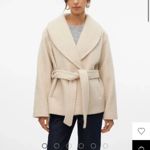 Beige kappa med bälte från Vero Moda - Stilren beige kappa från Vero Moda som jag knappt använt 2-3 gånger. Jackan har en klassisk omlottmodell och två fickor framtill. Perfekt för dig som gillar en clean och trendig look💕💕 Nypris 849kr Mitt pris 400kr! Men är öppen för prissänkning!!