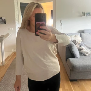 Beige stickad tröja med ribbade ärmar - Säljer en beige stickad tröja med rund hals och ribbade trekvarts ärmar. Tröjan har ett skönt och lätt material som gör den skön att bära. En basic tröja men väldigt fin!