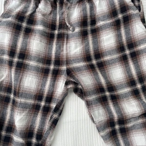 Rutiga mjukisbyxor med snörning - Supermysiga mjukis/pyjamas byxor från lager 157 i brun, svart och vit rutig design. Byxorna har elastisk midja med snörning och är gjorda i mjukt bomullstyg. Perfekta för chill dagar hemma eller när du vill vara extra bekväm.