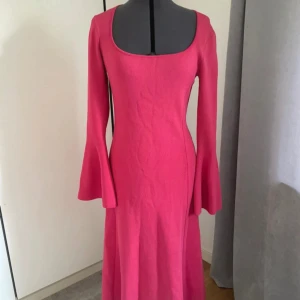 Rosa lång stickad klänning med trumpetärm - Supersnygg lång rosa klänning med trumpetärmar och fyrkantig ringning. Klänningen är stickad och har en figurnära passform som ger en cool siluett. Perfekt för dig som vill sticka ut med färg och form! 💖klänning är lite nopprig (se näst sista bild) 