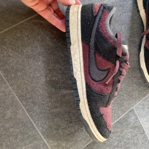 Nike Dunk Low vinröd/svart mocka - Nike Dunk Low sneakers i vinröd och svart med ruggad mocka över hela skon. Pris kan diskuteras 