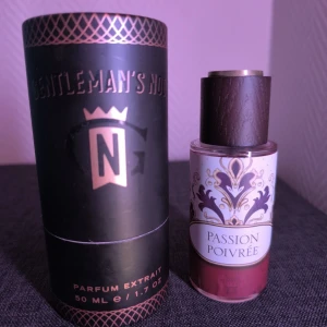 Gentleman's Nod Passion Poivrée Parfym - Exklusiv parfymflaska på 50 ml från Gentleman's Nod, Passion Poivrée. Flaskan är genomskinlig med röd vätska, elegant etikett i vitt, guld och svart samt ett lyxigt lock i trä och metall. Kommer i en svart rund förpackning med guldiga detaljer. https://gentlemansnod.com/products/passion-poivree-parfum-extrait