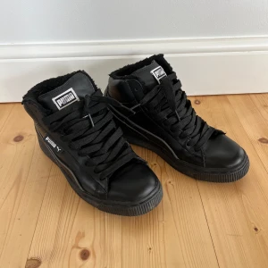 Svarta sneakers från Puma med foder - Svarta höga sneakers från Puma med klassisk logga på plös och sida. Skorna har snörning, rund tå och är fodrade med mjukt material för extra värme. I bra skick.