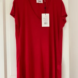 Röd v-ringad t-shirt från Isay - Riktigt snygg röd T-shirt från Isay med v-ringning och korta ärmar. Modellen är rak och lite loose, perfekt för en chill och stilren look. Tillverkad i mjuk och följsam viskos som känns skön mot huden.