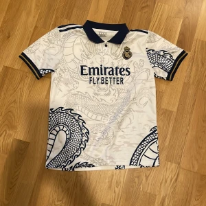 Real Madrid tröja - Snygg vit Real Madrid fotbollströja. Från drakens år. Tröjan är storlek L barn. 