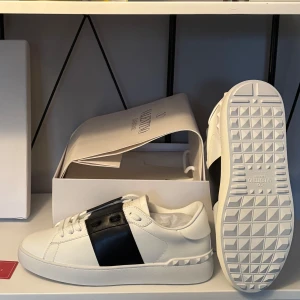 Valentino Garavani Open Sneakers vit/svart - Snygga Valentino Garavani Open sneakers som är perfekt till sommaren. Allt medföljer såsom alla kort,bag och en dustbag. Perfekt för dig som vill vara stilig