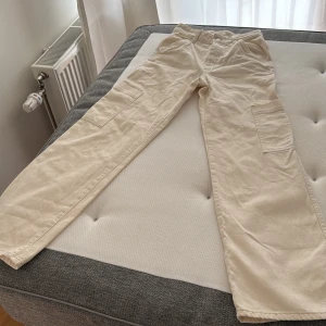 Beiga cargopants från H&M, stl 34 - Snygga beiga cargopants från H&M i storlek 34. Byxorna har raka ben, flera praktiska fickor på sidorna och klassisk dragkedja framtill. Tillverkade i 100% bomull. Perfekta för en chill och trendig look🤍