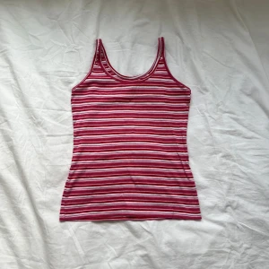 Randigt linne - Ett superfint randigt linne från Fresh Spirit i rött, rosa och vitt. Toppen har smala axelband och är figurnära med klassisk rund halsringning. Perfekt för varma dagar och enkel att matcha med jeans eller kjol.