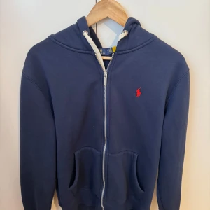 Ralph lauren zip hoodie - Stilren hoodie ifrån Ralph lauren i storlek L, sitter mer som M! Skick 10/10 använd 2-3 gånger. Nypris ligger på 2199kr