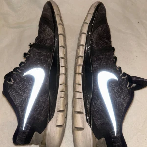 Nike Free 5.0, löparskor, svart, EUR 38.5 - Ett par begagnade Nike Free 5.0 löparskor i svart färg. Skorna har en vit Nike-logga på sidan och svarta skosnören.